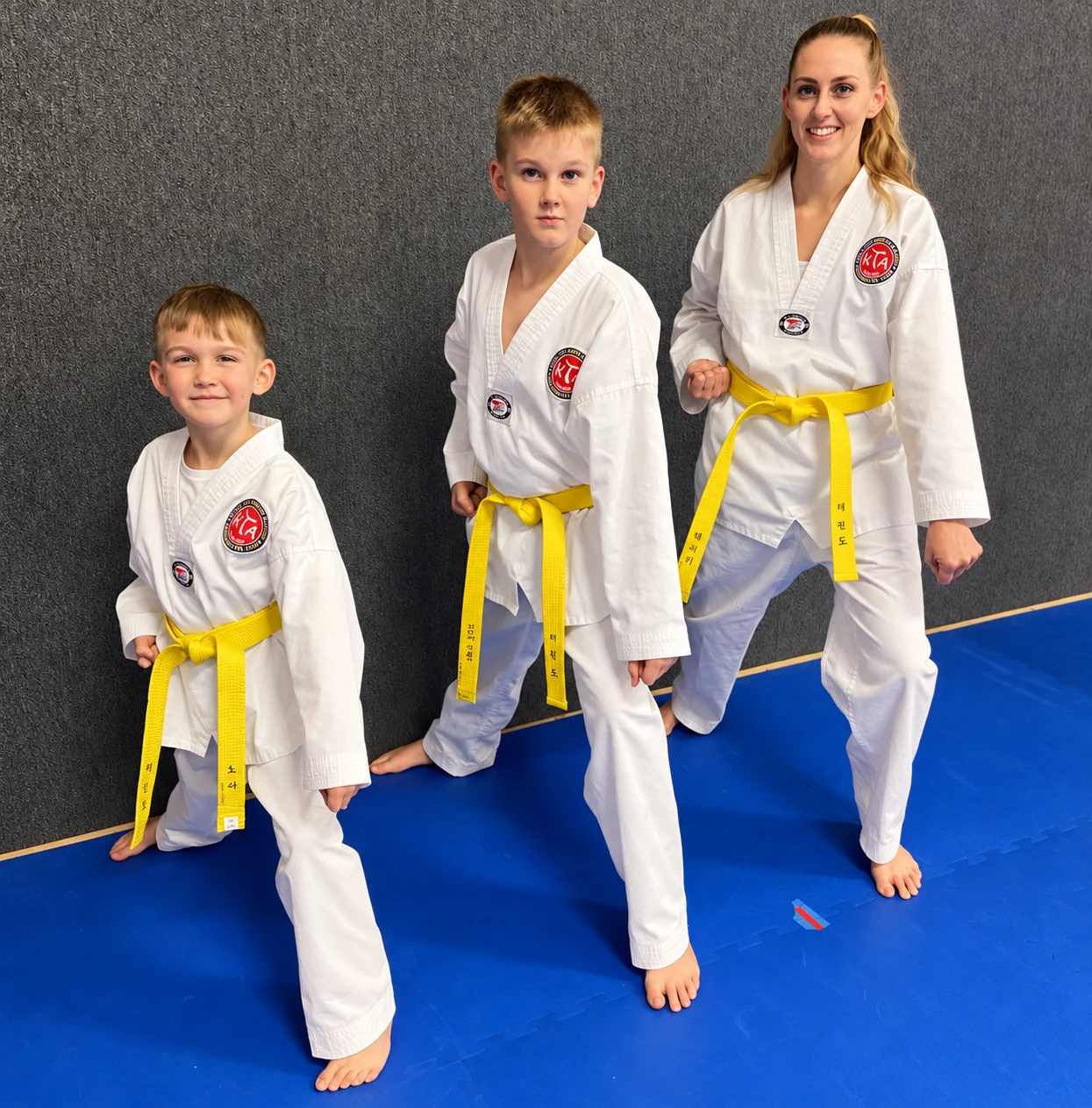 An adult and two children in martial-arts uniforms.