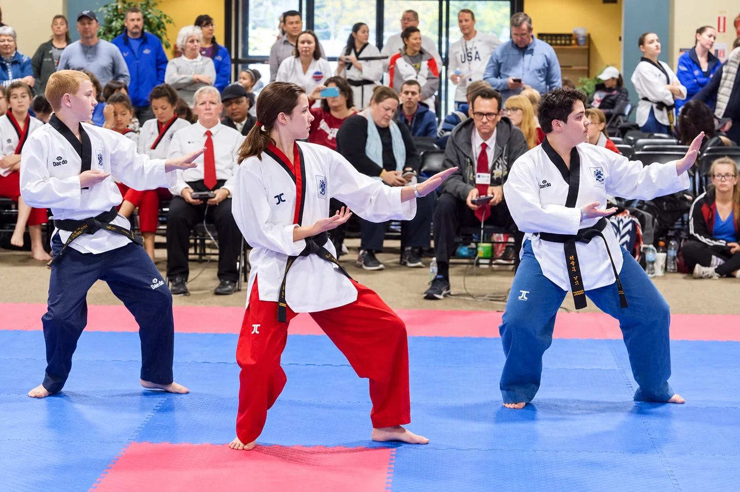Three martial artists performing at a competition.