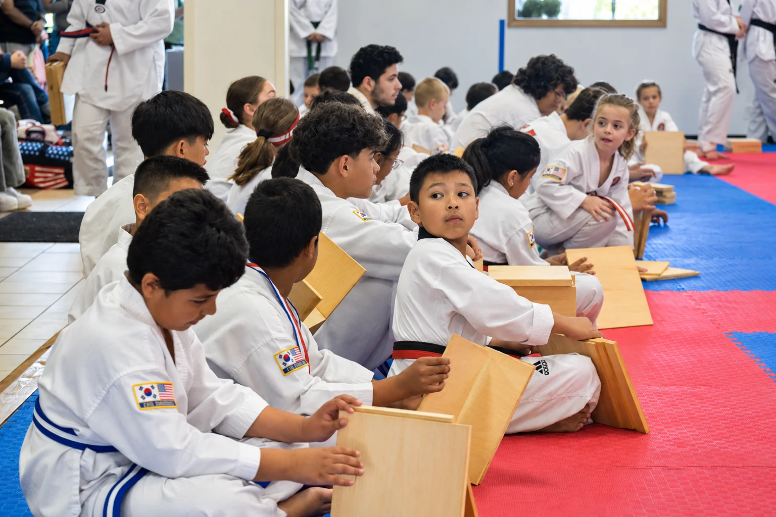 KTA students sit in an orderly line with breaking boards during Taekwondo training in Noblesville